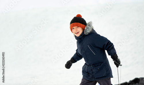 childhood, sledging and season concept - happy little boy with sled in winter outdoors