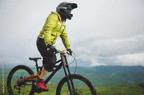 A man in a mountain helmet riding a mountain bike rides around the beautiful nature in cloudy weather. downhill