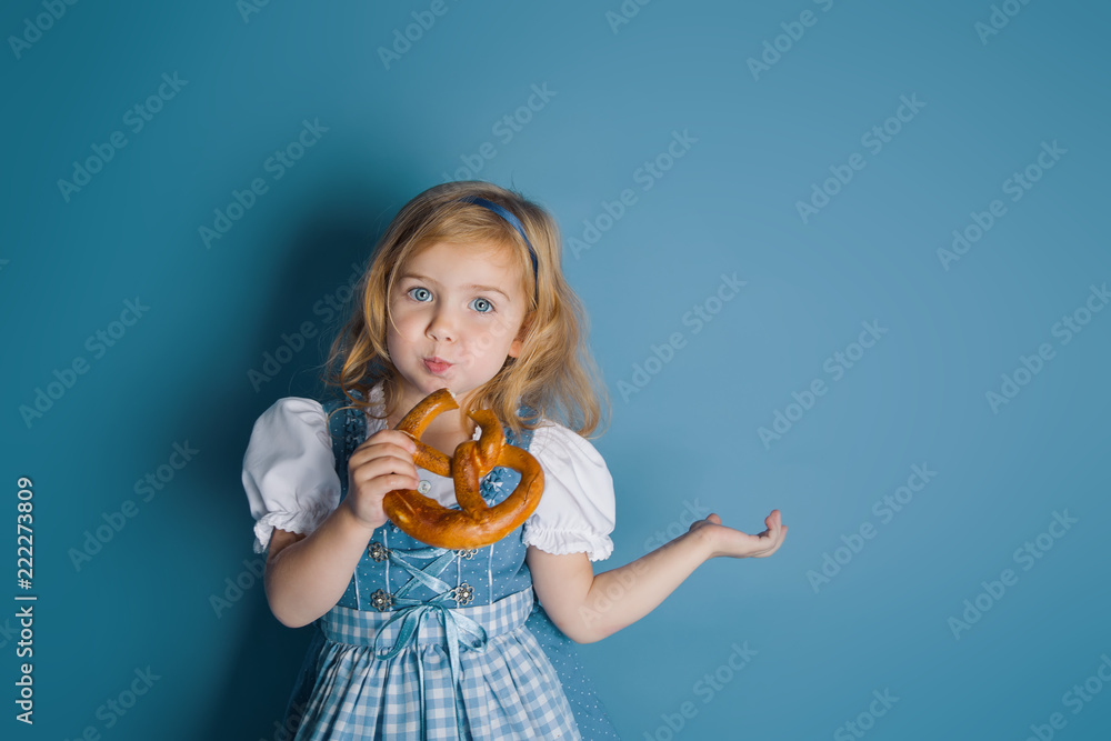 Little girl in traditional german dress dirndl eating bretzel