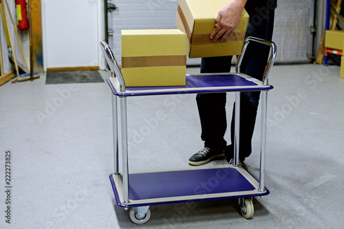 Man collects cardboard boxes to material handling trolley in warehouse