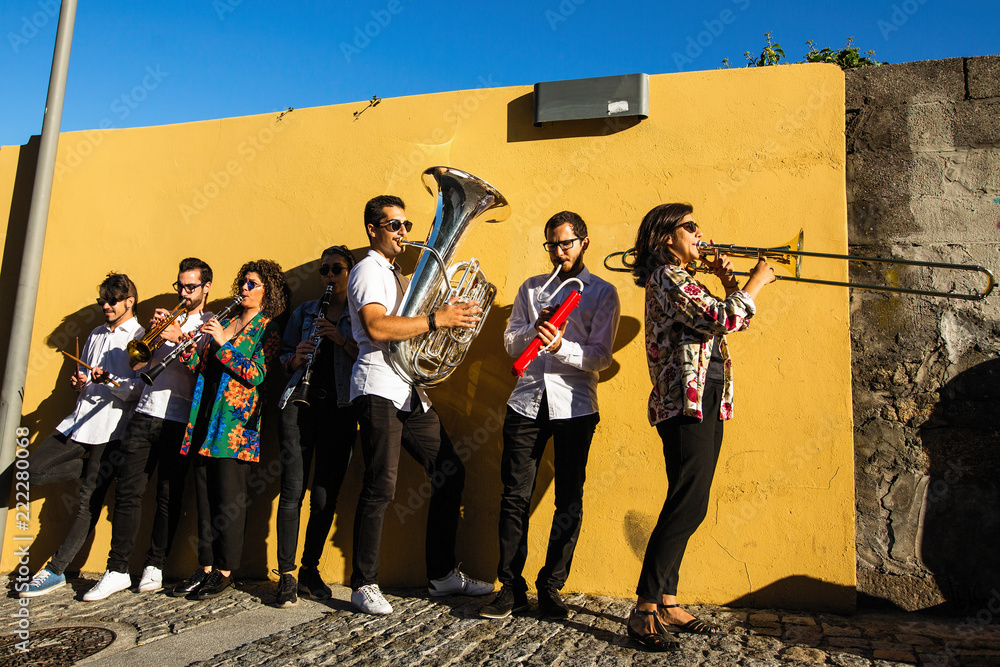 Obraz premium Jazz band, a group of musicians play music on the street near the yellow wall.
