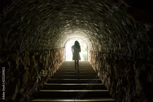 Canvas Print Girl walking throug dark tunnel into light
