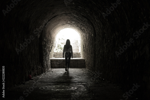 Obraz na plátně Girl walking throug dark tunnel into light