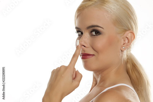 Portrait of beautiful blonde woman touching her nose on white background