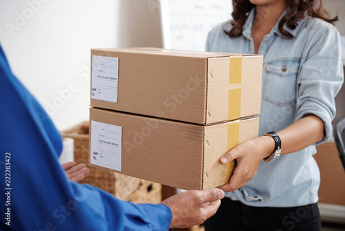 Young postwoman giving package to the man at post office