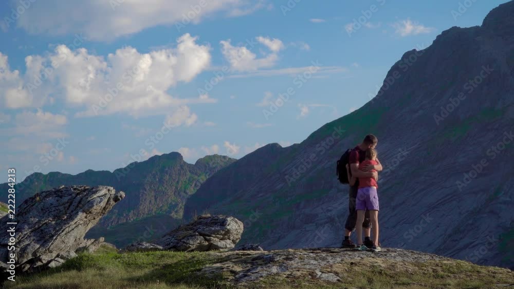Father and daughter are traveling in the mountains. They embrace and are happy to travel in the Lofoten mountains. Norway. Father and daughter are traveling in the mountains. They embrace and are happy to travel in the Lofoten mountains. Norway.