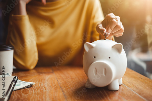 Fototapeta hand put money coin into piggy for saving money wealth
