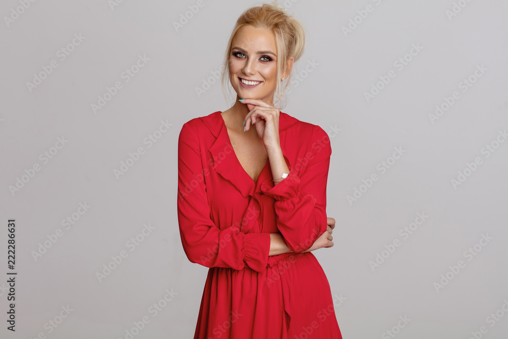 Beautiful smiling blond woman in red dress isolated on gray background Beautiful smiling blond woman in red dress isolated on gray background