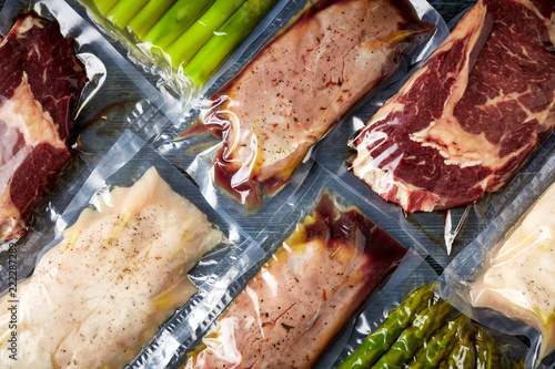 Meat and asparagus vacuum sealed on black table, from above