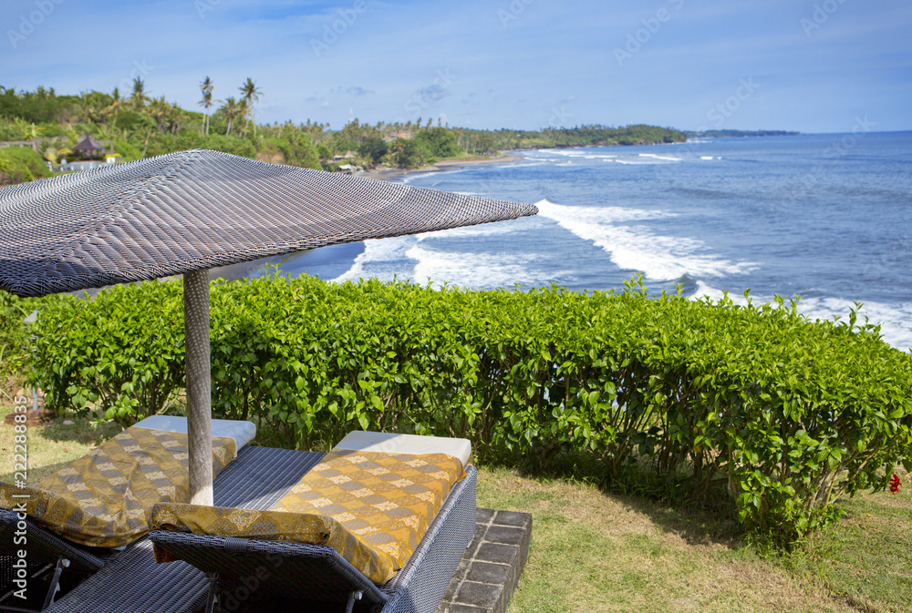 Fototapeta premium Bali, Indonesia. Beds under the beach umbrella overlooking the sea on the edge of the cliff