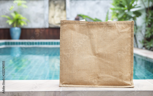 Design jute bag over blurred swimming pool background, ecological product concept