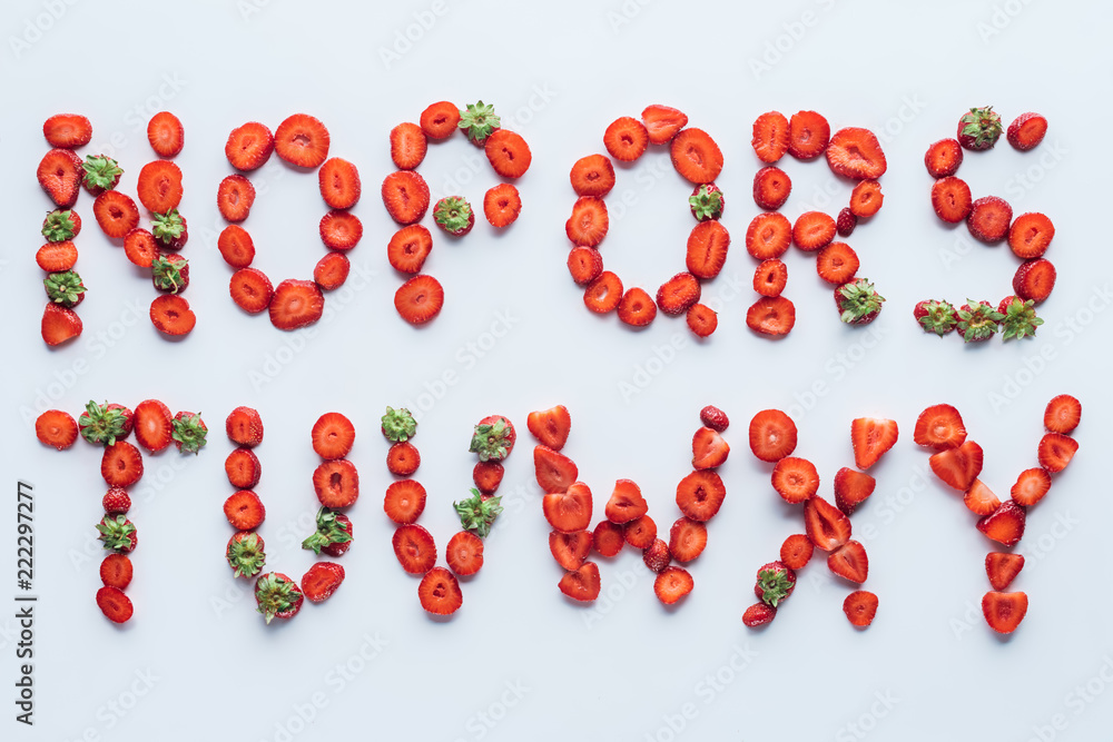 top view of part of alphabet letters made of fresh sliced strawberries on white surface top view of part of alphabet letters made of fresh sliced strawberries on white surface