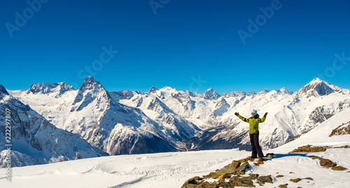 A girl at the top of the mountain looks at the snowy mountains