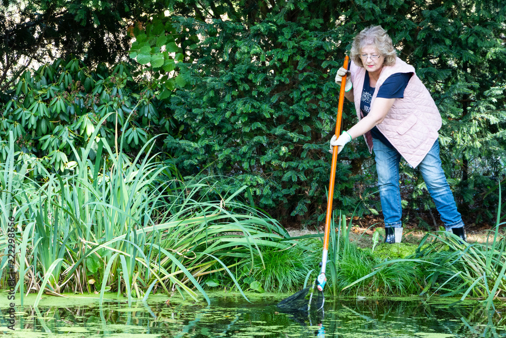 Foto de Frau entfernt mit einem Kescher Wasserlinsen aus einem