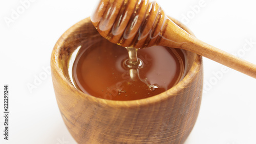 honey dripping from wooden dipper on white background