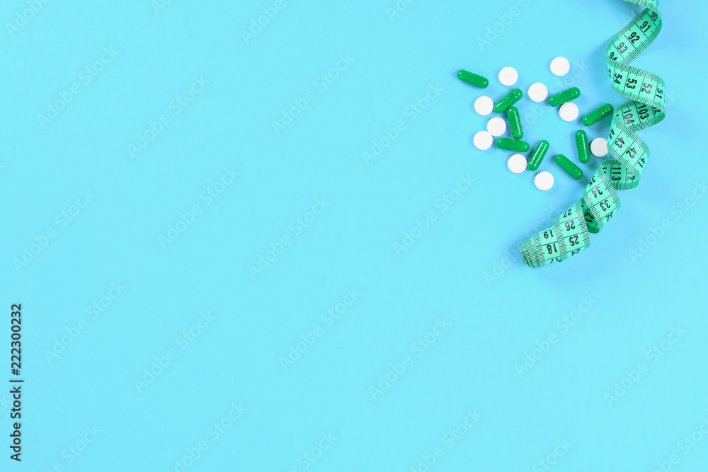The concept of losing weight. Measuring tape, centimeter tablets, pills on a blue table background. Top view, copy space, flat lay. The concept of losing weight. Measuring tape, centimeter tablets, pills on a blue table background. Top view, copy space, flat lay.