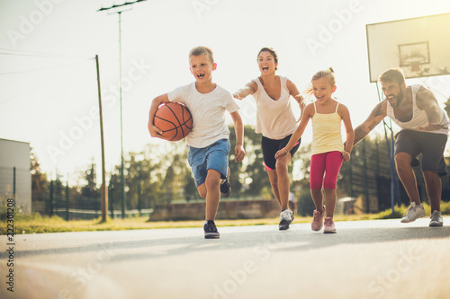 Spring is great for family sport. Happy family playing basketball outside.