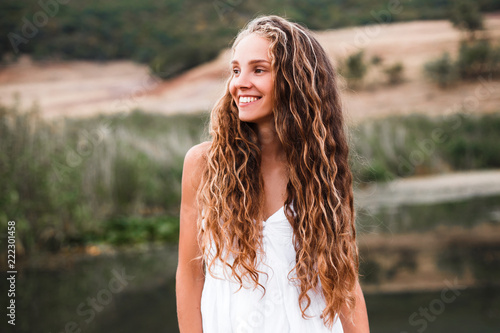 Close-up portrait of a beautiful smiling blonde girl with natural curls.