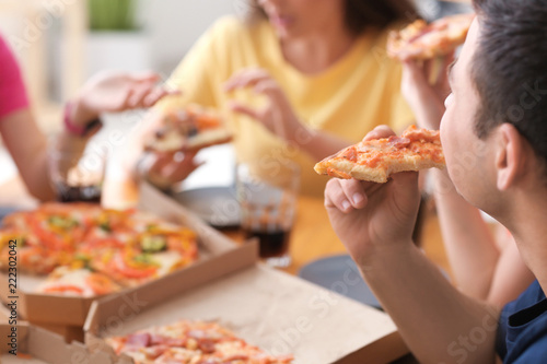 Young people eating pizza at table indoors