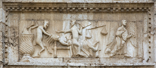 Angels and demons on medieval bas-relief, from the facade of Saint Peter church, Spoleto, Italy.
