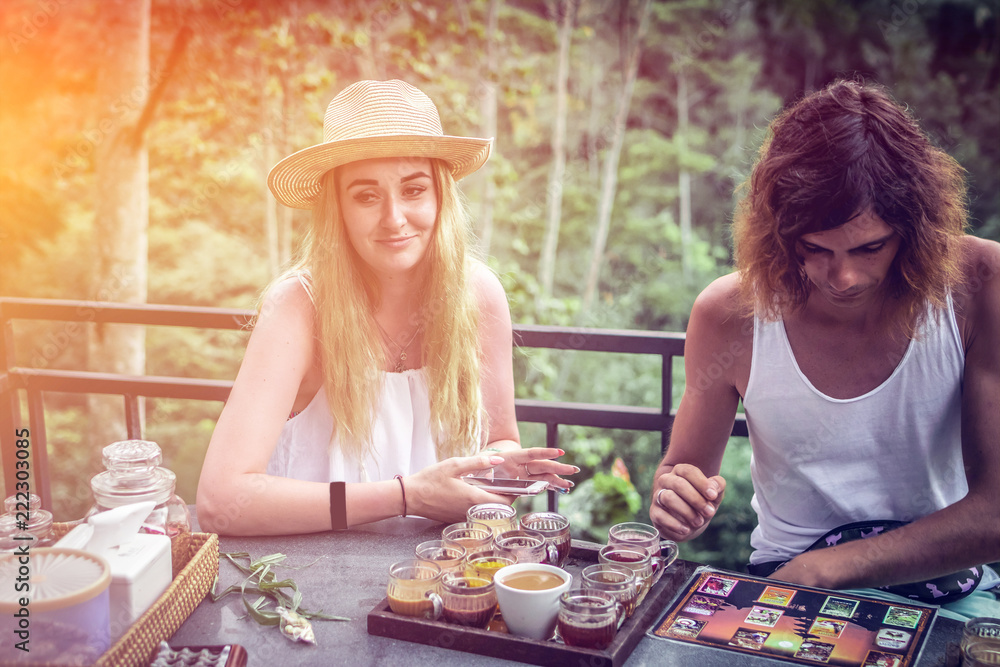 Fototapeta premium Young couple coffee and tea tasting during sunset in the jungle rainforest of a tropical Bali island.