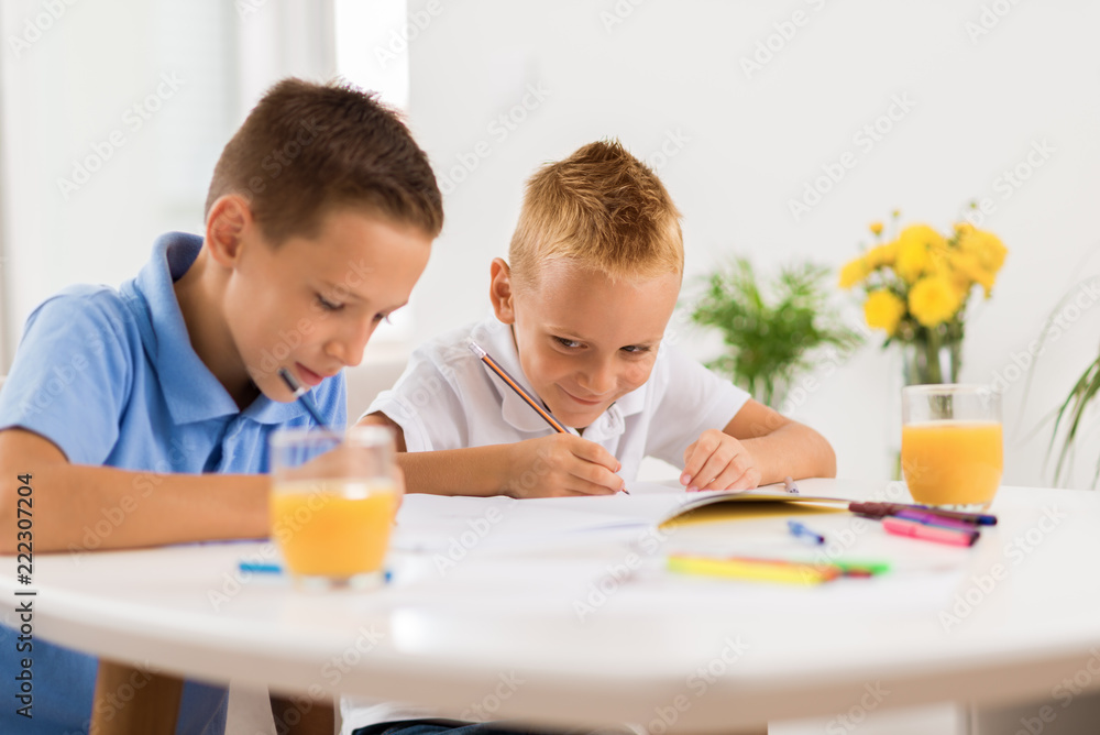 Young boys writing in notebooks at home Young boys writing in notebooks at home