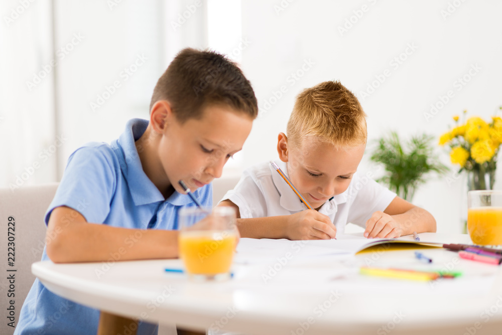 Young boys writing in notebooks at home Young boys writing in notebooks at home