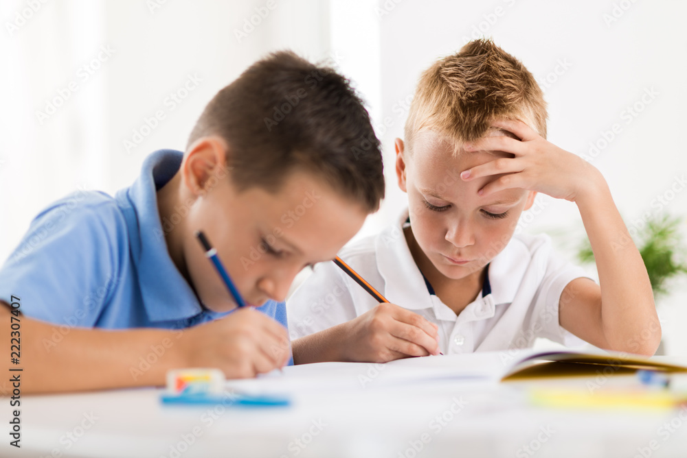 Young boys writing in notebooks at home Young boys writing in notebooks at home