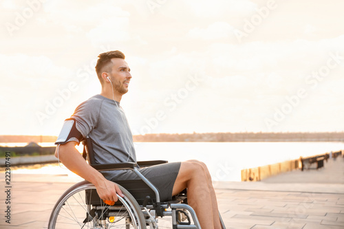 Young man in wheelchair listening to music outdoors