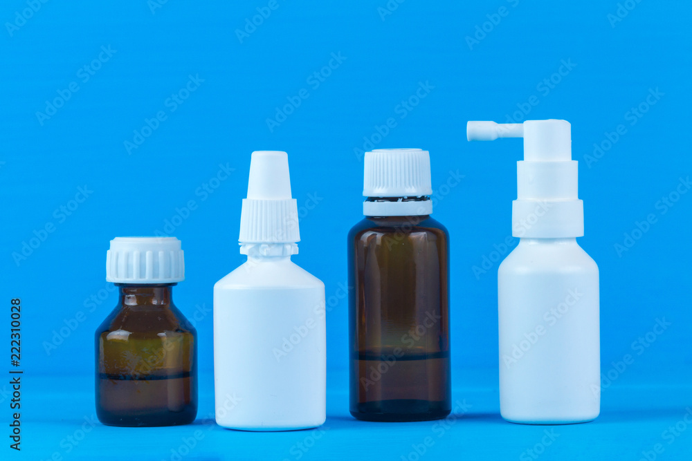 Bottles and sprays with medicine for flu and colds on a blue background. Various drugs for the sore throat and stuffy nose. Treatment of colds Bottles and sprays with medicine for flu and colds on a blue background. Various drugs for the sore throat and stuffy nose. Treatment of colds