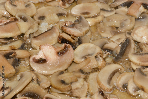 pieces of champignons with onions are fried in a frying pan with butter