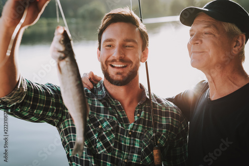 Old Father with Bearded Son Fishing on River. photo