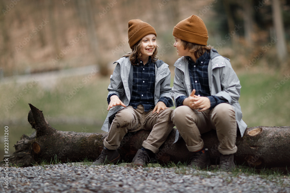 Fototapeta premium smiling boys talking while sitting on the big log