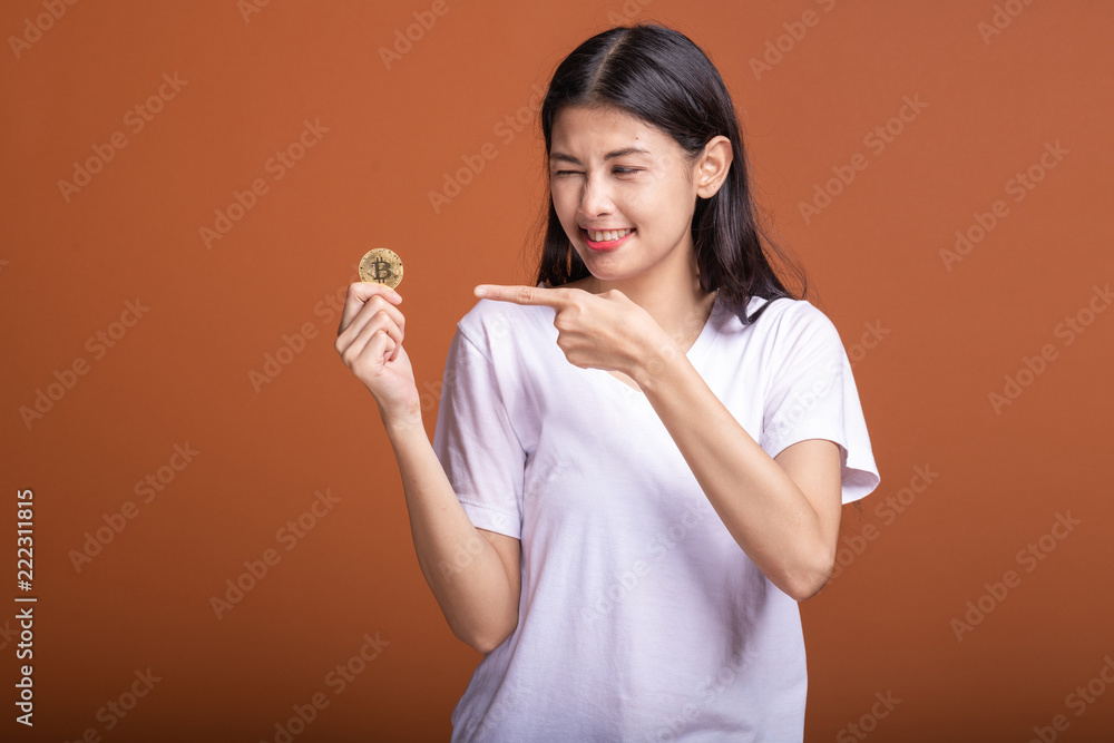 Woman holding bit coin isolated in orange background. Woman holding bit coin isolated in orange background.