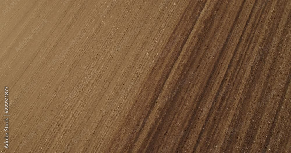 An aerial shot of a farmer in tractor cultivating arable land field just before seeding, sowing season. An aerial shot of a farmer in tractor cultivating arable land field just before seeding, sowing season.