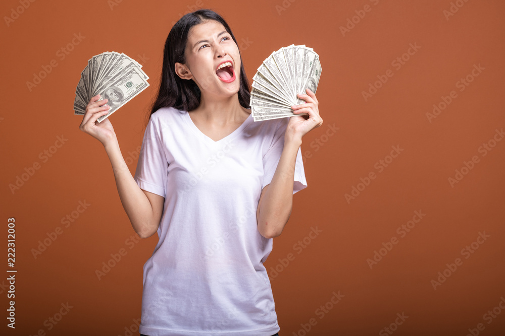 Woman holding cash notes isolated in orange background. Woman holding cash notes isolated in orange background.