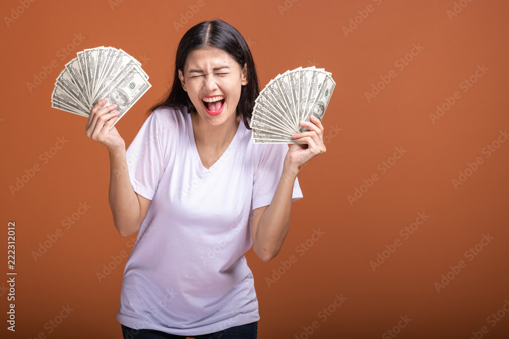 Woman holding cash notes isolated in orange background. Woman holding cash notes isolated in orange background.