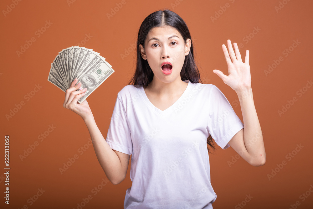 Woman holding cash notes isolated in orange background. Woman holding cash notes isolated in orange background.