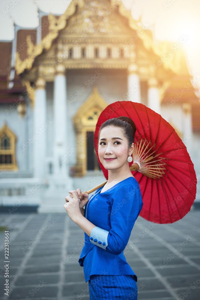 Woman tourist with red traditional Thai umbrella at Wat Benchamabophit the marble temple in Bangkok, Thailand