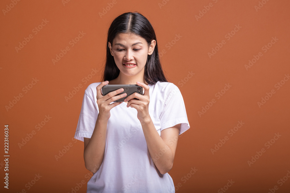 Woman playing mobile game isolated over orange background. Woman playing mobile game isolated over orange background.