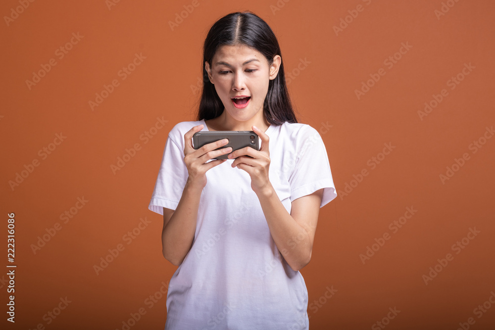 Woman playing mobile game isolated over orange background.