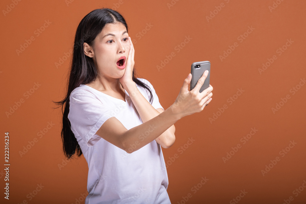 Woman using mobile phone isolated over orange background. Woman using mobile phone isolated over orange background.