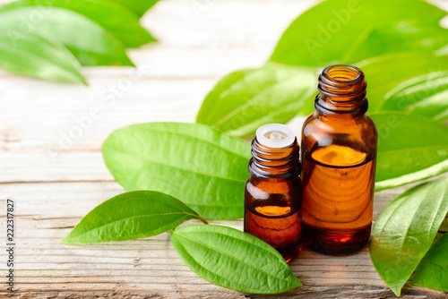 cinnamon leaf oil in the glass bottle, with fresh cinnamon leaf, on the wooden board