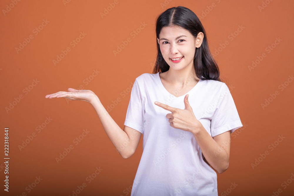 Woman pointing finger with open palm over orange background. Woman pointing finger with open palm over orange background.