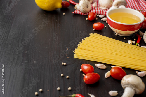 Spaghetti ingredients on black wooden desk  top view.