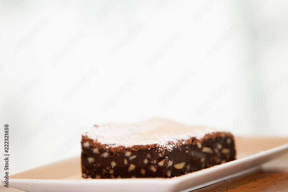 a brownie on a square plate with powdered sugar on top a brownie on a square plate with powdered sugar on top