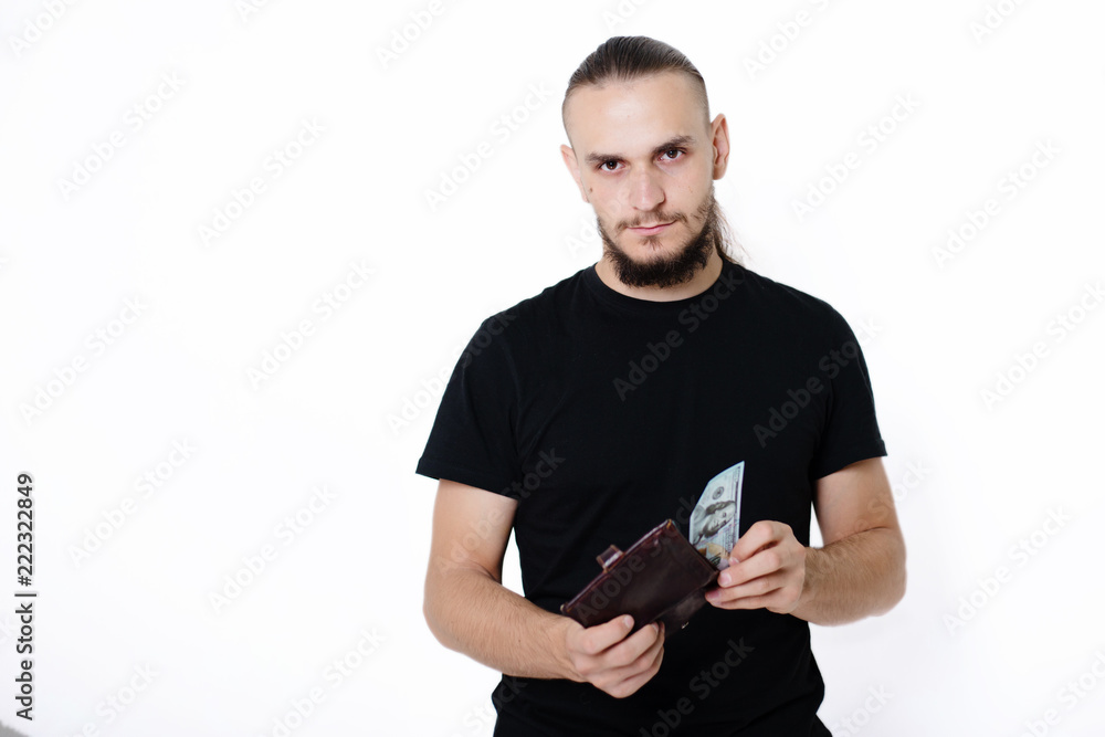 Young handsome guy in a black T-shirt on a white background holds dollars in his hands. Man with money Young handsome guy in a black T-shirt on a white background holds dollars in his hands. Man with money