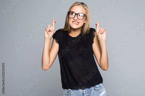 Fototapeta Young beauty woman keeps fingers crossed, hopes for good luck, isolated against