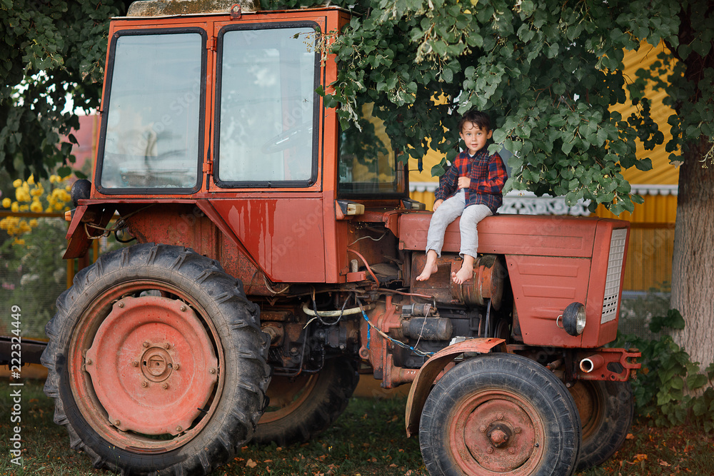 boy sitting on the tractor under the tree boy sitting on the tractor under the tree