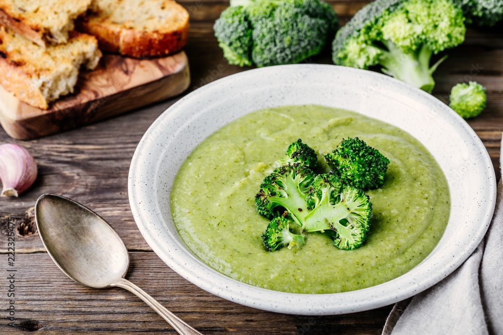Homemade broccoli cream soup in white bowl with toasts on wooden background Homemade broccoli cream soup in white bowl with toasts on wooden background